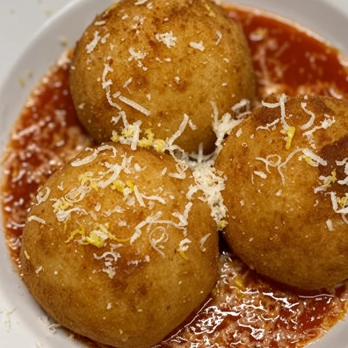 Three cheese arancini in tomato sauce with grated cheese